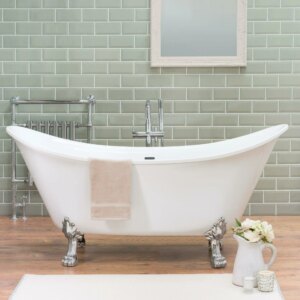A pristine white freestanding double-slipper clawfoot bathtub with polished chrome feet set against glossy sage green subway wall tiles and laminate wood flooring.